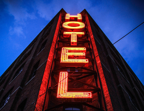 Looking up at a bright neon hotel sign