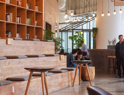 Well-lit lobby with bookshelves, artwork hanging from the ceiling with rows of stadium style seating