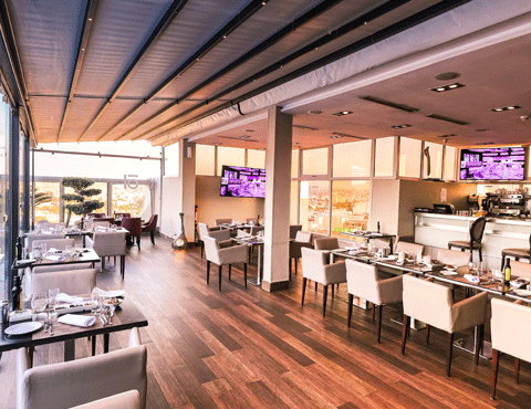 Interior of an empty restaurant with a lot of natural light, hardwood floors and lightly colored seating