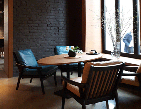 Seating area with an oval wooden table and dark brown and tan leather chairs by a large window